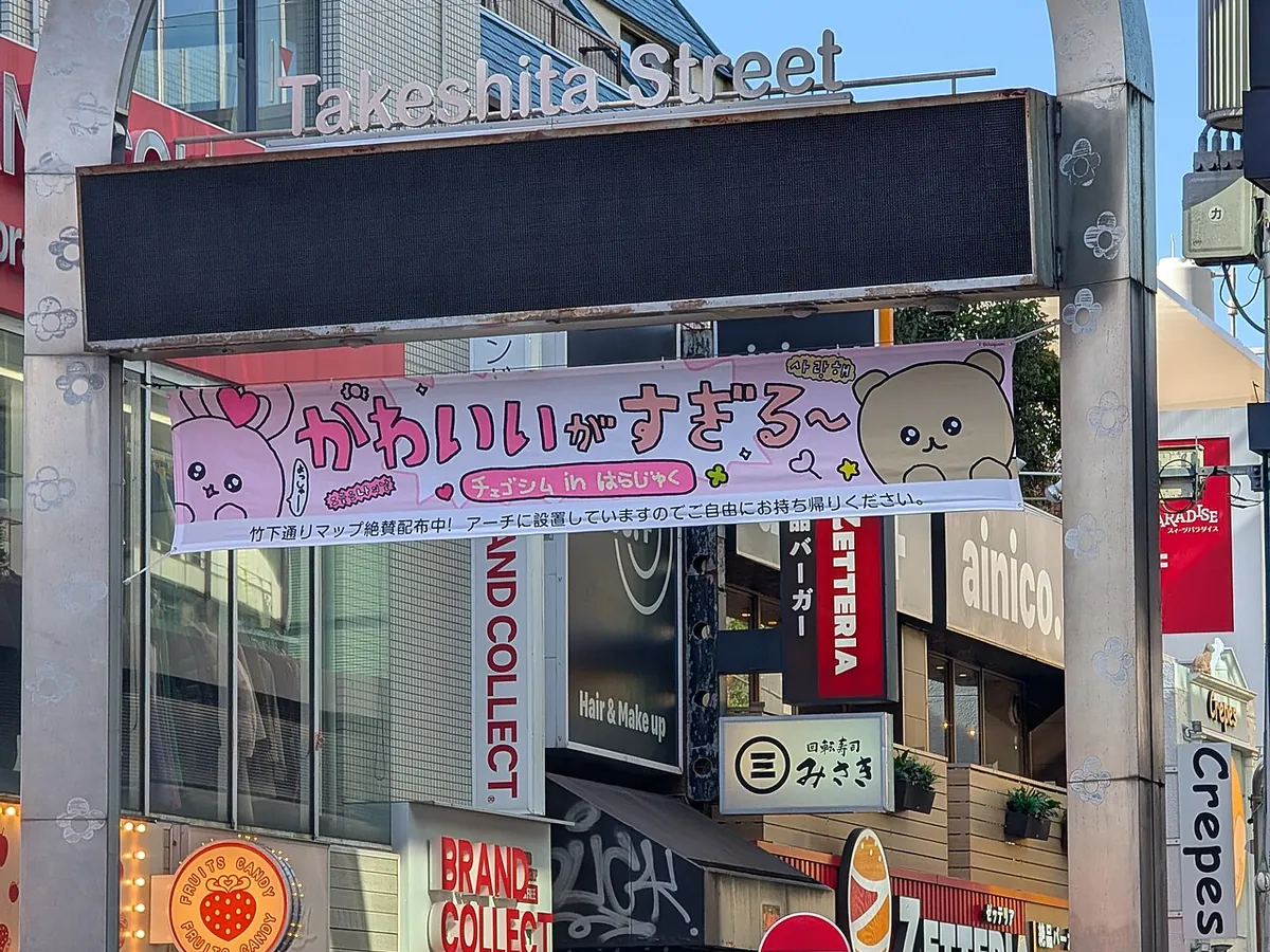 The entrance arch to Takeshita Street in Harajuku, busy with shoppers below its signage
