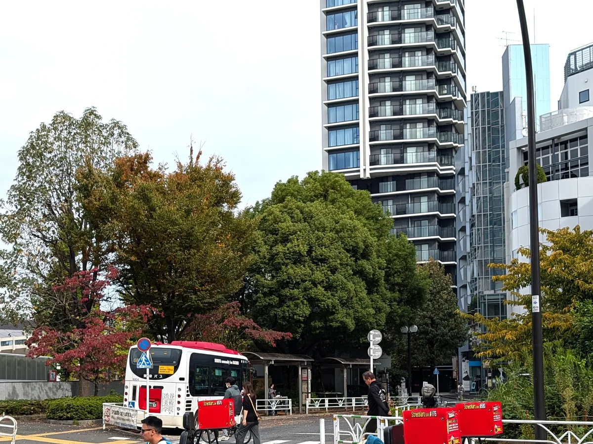 Street-legal go-karts waiting at a Tokyo junction in daylight, drivers seated low in the traffic lane